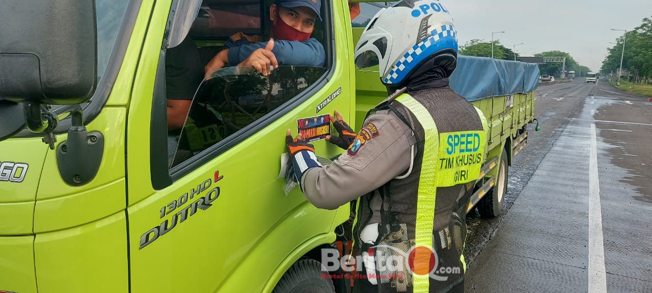 Petugas kepolisian Polres Gresik menempelkan stiker ayo pakai masker